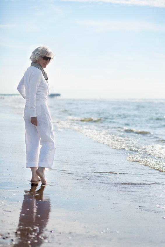 attraktive, grauhaarige Frau geniet Spaziergang am Meer