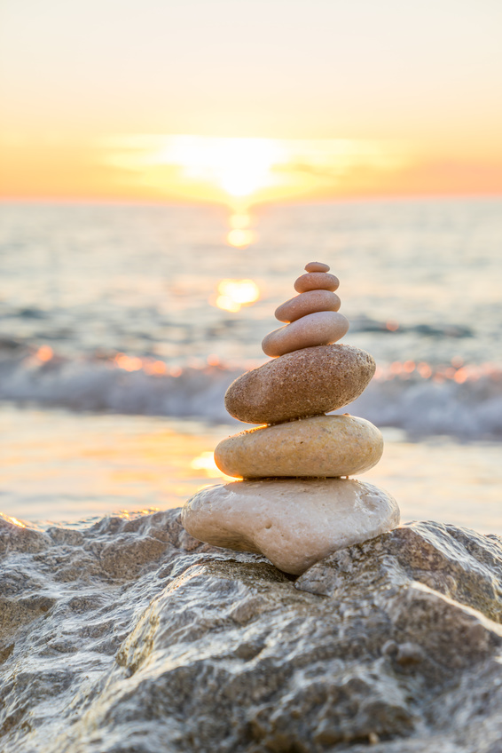 Stones pyramid on sand symbolizing zen, harmony, balance. Ocean in the background